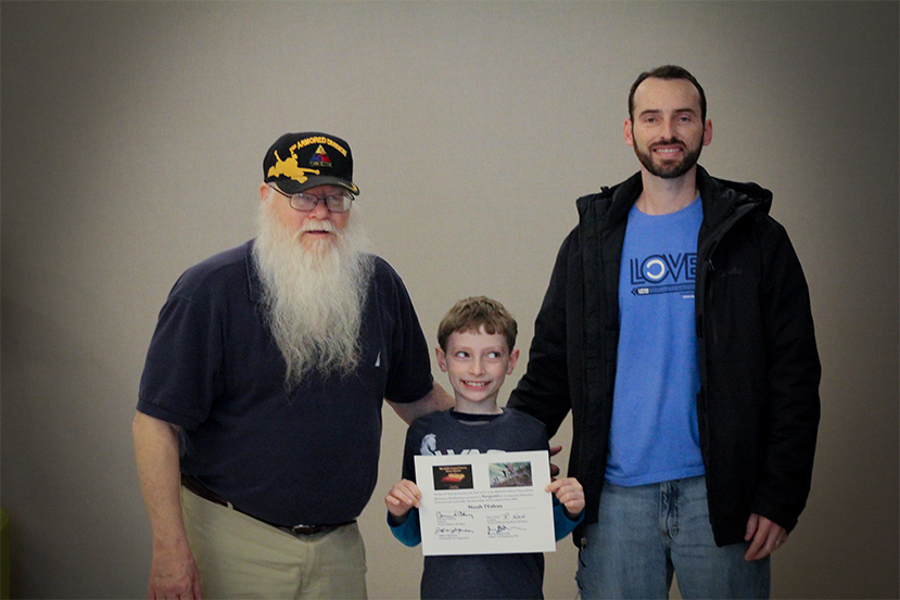 Jim Hollingsworth (left) promoting Noah Mahan (center) to Sergeant in the Texas Chess Militia.  Noah's proud Father, Joel Mahan, is on the right.